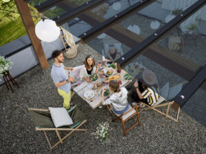 Group of Friends dining under a Pergola with an EZ Glaze roofing system installed